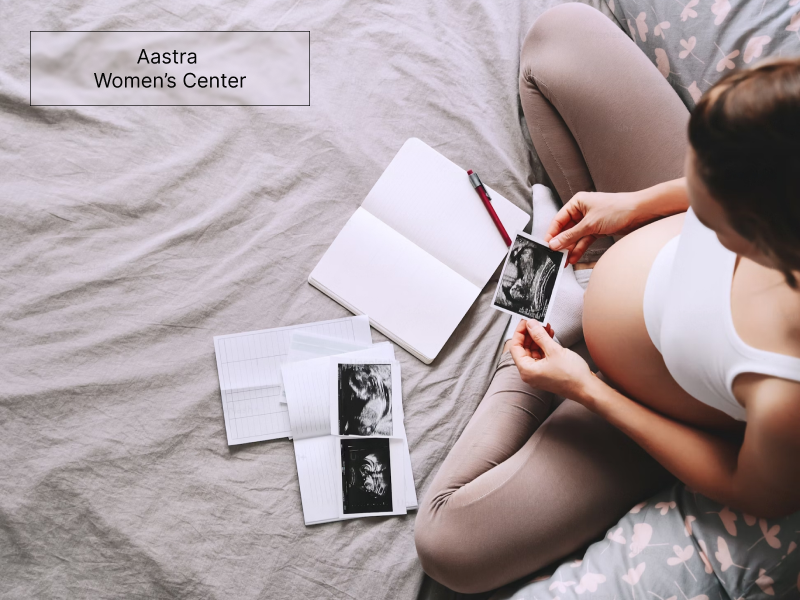 The image shows a pregnant woman writing on her pregnancy journal.